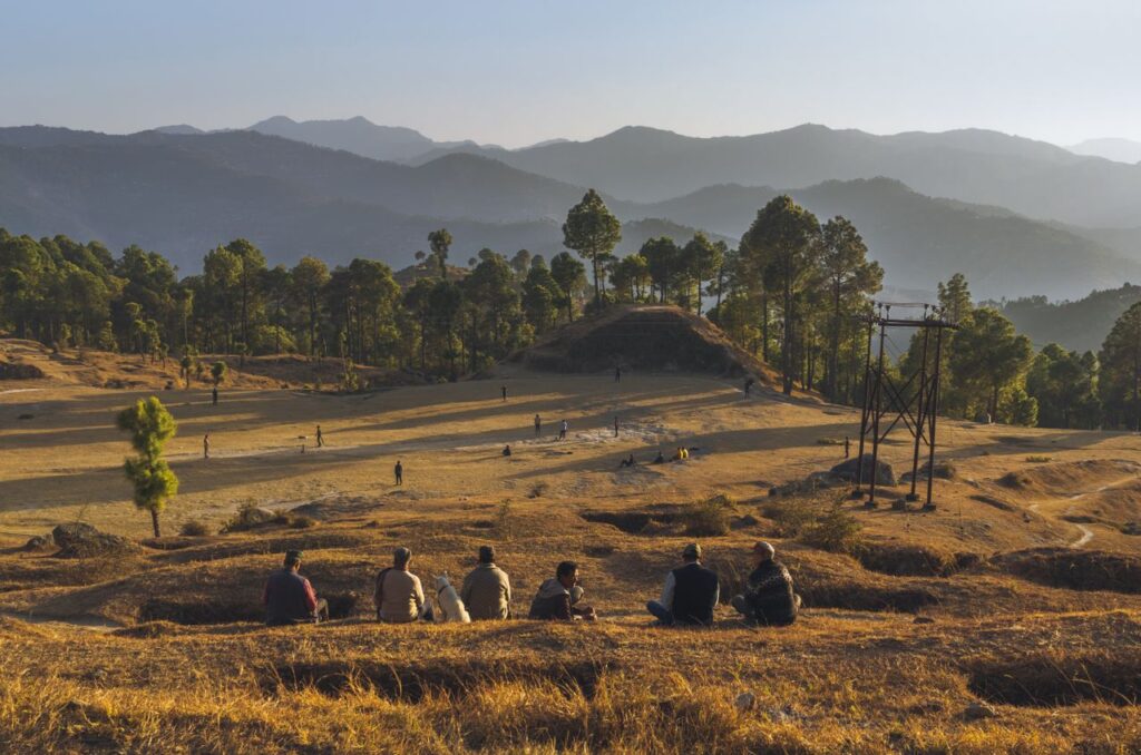 A peaceful rural landscape with people sitting and enjoying the natural scenery in the mountains.