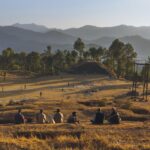A peaceful rural landscape with people sitting and enjoying the natural scenery in the mountains.