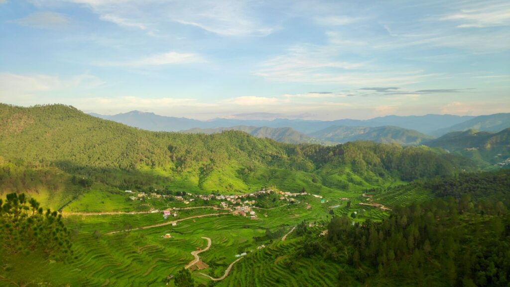 A scenic aerial view of lush green hills and terraced fields in Uttarakhand, India, perfect for nature and travel enthusiasts.