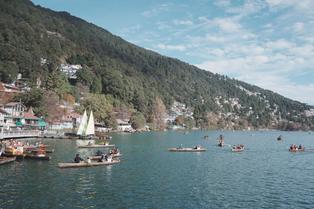 People enjoying boating on a picturesque lake surrounded by lush green mountains.