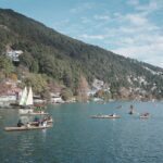 People enjoying boating on a picturesque lake surrounded by lush green mountains.