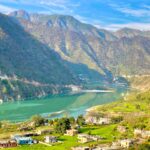 Picturesque view of a serene village nestled by a river in a mountain valley, Uttarakhand