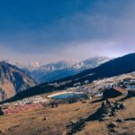 Scenic landscape of Auli, India with snowy mountains and a serene lake in winter.